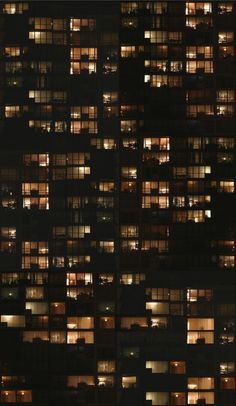 many windows are lit up at night in the building's dark colors and patterns