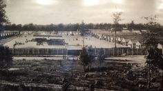 an old black and white photo of a town with lots of trees in the foreground