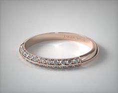 a rose gold wedding band with diamonds on the sides and an engraved name on the side