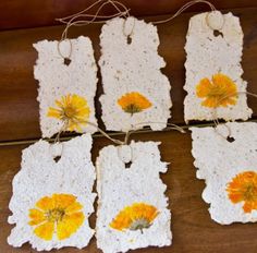 four crocheted tags with yellow flowers on them sitting on a wooden table top