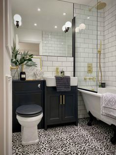 a white toilet sitting next to a bath tub in a bathroom under a large mirror