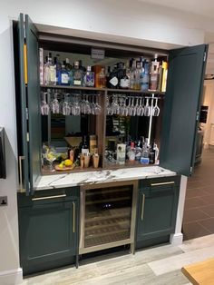 a bar with wine glasses and liquor bottles on the shelves in a room that has tile flooring