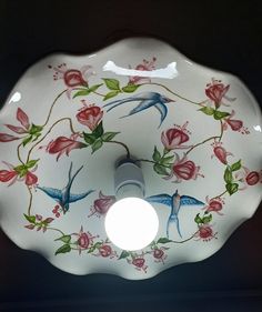 a glass bowl with flowers painted on the side and a light bulb in the middle