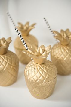 some gold pineapple cups are sitting on a table