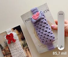 a crocheted bookmark is being held by a person's hand next to two books