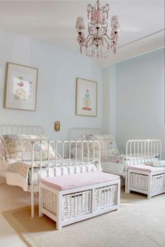 a bedroom with two white beds and a chandelier