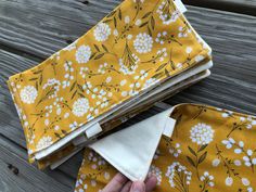 two yellow and white cloths are folded on top of each other, with one person's hand holding the fabric