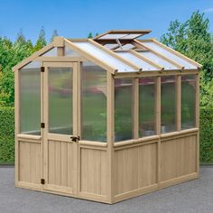 a small wooden greenhouse with glass doors on the roof and side walls, in front of a hedge