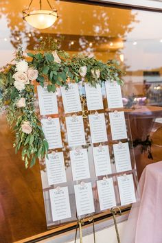 the seating cards were placed on a stand with greenery and pink flowers for an elegant touch