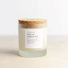 a white candle with a cork lid sitting on a wooden table next to a wall