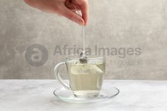 a person is pouring tea into a glass cup