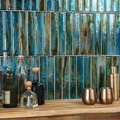 several bottles and glasses on a shelf in front of a mosaic tile backsplash