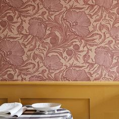 a table with two plates on it in front of a wallpapered background that looks like flowers