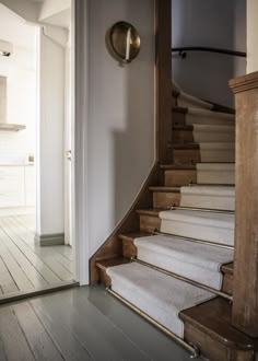 an open door leading to a staircase with carpeted steps and wood trimmings