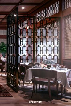 a dining room with tables and chairs in front of an open screen wall that has decorative glass panels on it