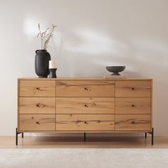 a large wooden dresser sitting next to a vase on top of a hard wood floor