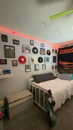 a bed room with a neatly made bed and lots of pictures on the wall above it