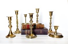 several brass candlesticks and books on a table