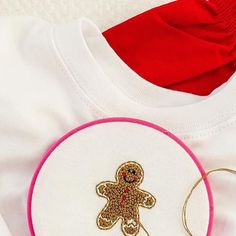 a white t - shirt with a pink trim and a gold teddy bear on it