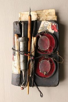 an old book with various items attached to it, including two chopsticks and one candle