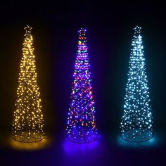 three christmas trees are lit up in the dark with colorful lights on each one tree