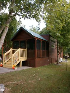 a small cabin sits in the middle of a wooded area with stairs leading up to it