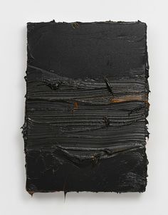 an abstract piece of black paint on a white surface with thin strips of dark brown paint