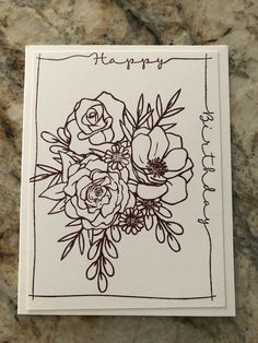 a card with flowers and the words happy on it in cursive writing, sitting on a marble surface