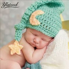 a baby wearing a green crochet hat with stars on it's side