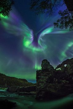 an image of the aurora bore in the sky above some rocks and water at night