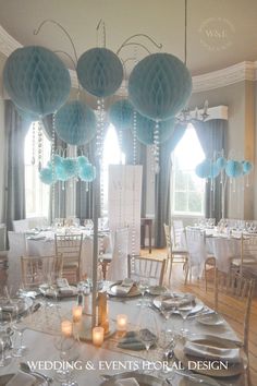 a table set up for a wedding with blue paper lanterns