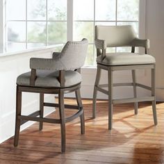 two chairs sitting next to each other on top of a hard wood floor in an empty room