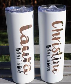 two white tumblers sitting on top of a wooden picnic table next to each other