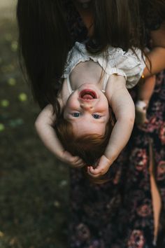 a woman holding a baby up to her face while she holds it in the air