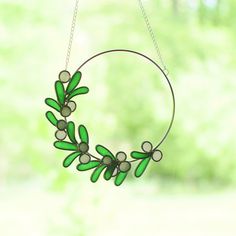 a green wreath hanging from a chain on a window sill with trees in the background