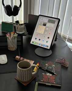 an ipad is sitting on a desk next to a cup of coffee and headphones