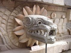 a stone dragon head is on display at the entrance to an ancient building in mexico