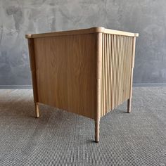 a wooden cabinet sitting on top of a carpeted floor next to a gray wall