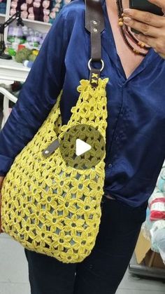 a woman is looking at her cell phone while wearing a yellow purse with an owl on it