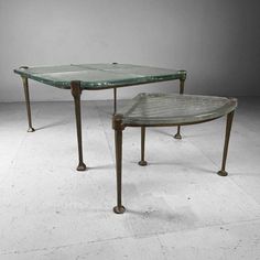 two metal tables with glass tops sitting on top of each other