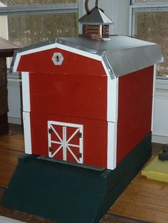 a red and white barn sitting on top of a wooden floor next to a window