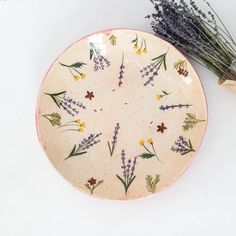 a plate with flowers on it next to a wooden spoon and some dried lavenders