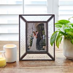 a photo frame sitting on top of a wooden table next to a potted plant