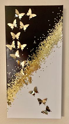 a painting with gold and white butterflies on it's side, in front of a black background