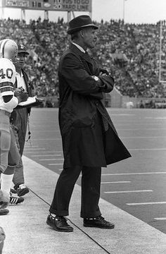 an old black and white photo of two men on a football field, one wearing a hat