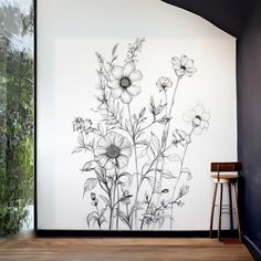 a black and white drawing of flowers on a wall next to a stool with a plant in it