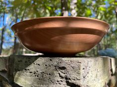 a brown bowl sitting on top of a rock