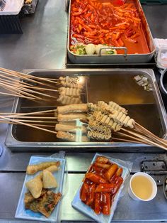 several trays filled with food sitting on top of a metal counter next to other foods