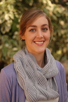 a smiling woman wearing a gray knitted scarf