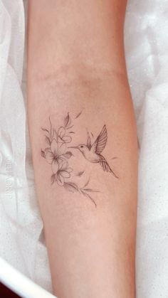 a woman's arm with flowers and a hummingbird tattoo on her left leg